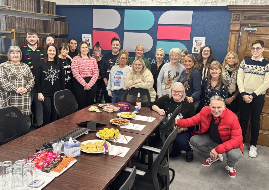 BBE Team in Christmas Jumpers around the boardroom table full of homemade cakes and mince pies