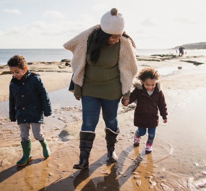 Mother and children walking along the beach in wellies and winter coats