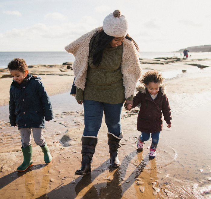 Mother and children walking along the beach in wellies and winter coats